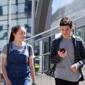 Students walking on campus with phone