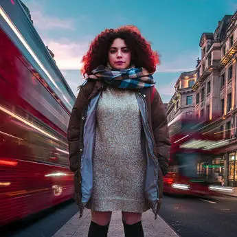 Student standing in London looking at the camera with a red bus going past in the background