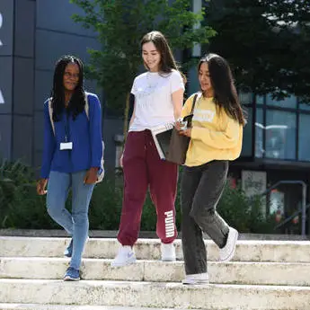 3 female students walking down some steps outside the library