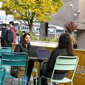 Students with laptop outside cafe on campus